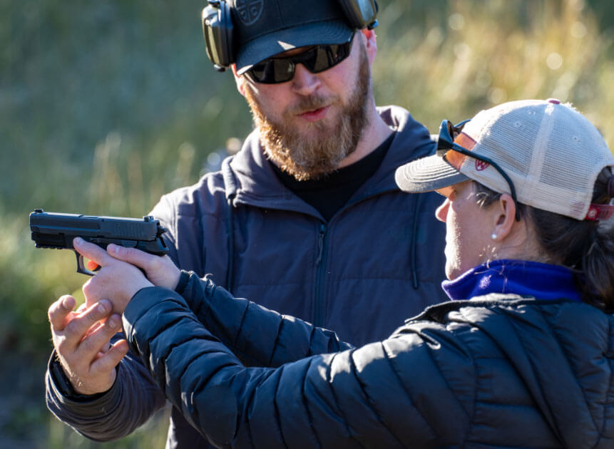 Gun safety instructor teaches woman with handgun at Alaska Tactical